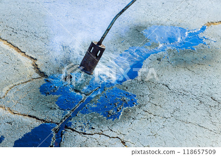 Heating cracks in asphalt before they are filled with hot bitumen emulsion is joint seal restorer at parking lot Heating cracks in asphalt before they are filled with hot bitumen emulsion is joint seal restorer at parking lot 118657509