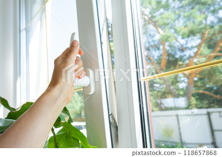 The hand holds the handle of a plastic double-glazed window, closing and opening the window with a rotary mechanism, the position of the handle for ventilation, micro-ventilation 118657868
