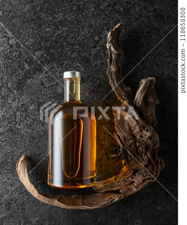 Bottle of whiskey and old snags on a black stone background. Bottle of whiskey and old snags on a black stone background. 118658308