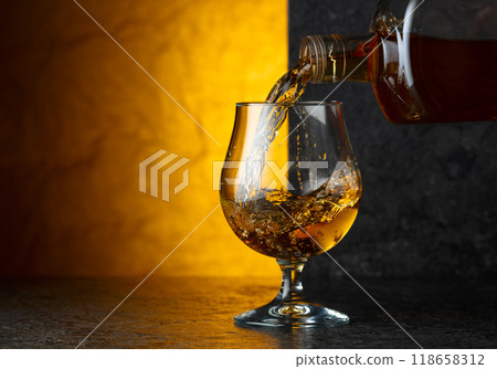 Pouring brandy from a bottle into a glass. Pouring brandy from a bottle into a glass. 118658312