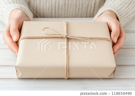 A woman presents a beautifully wrapped gift in simple brown paper 118658490