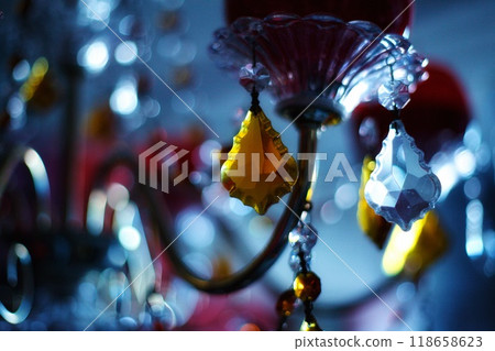an abstract dark photo with a chandelier and candelabra hung with Venetian crystal of different colors. beautiful weighing pieces of glass in the form of crystals. antique style room decoration and an abstract dark photo with a chandelier and candelabra hung with Venetian crystal of different colors. beautiful weighing pieces of glass in the form of crystals. antique style room decoration and 118658623