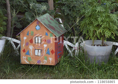 miniature house on the grass surrounded with green plants 118658865