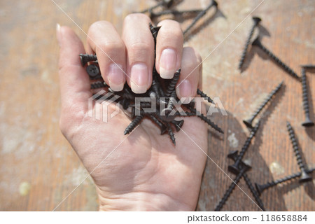 selective focus at the female hand, holding screws, concept of strong 118658884