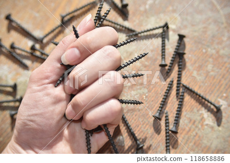 selective focus at the female hand, holding screws, concept of tight 118658886