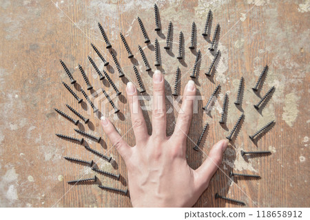 the hand surronded ith screws on the old wooden table the hand surronded ith screws on the old wooden table 118658912