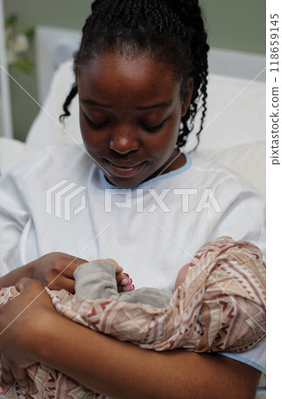 Mother Cradling Newborn Baby in Maternity Ward 118659145