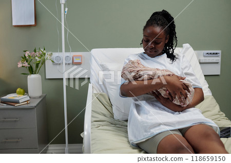 African American Mother Cradling Newborn Baby in Hospital Room 118659150