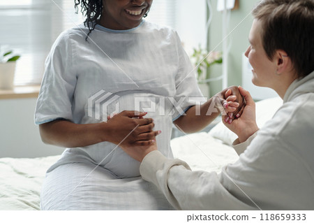 Supporting Pregnant Woman While Holding Hands and Smiling 118659333