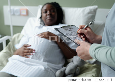 Pregnant Woman Talking with Doctor in Hospital Room 118659401