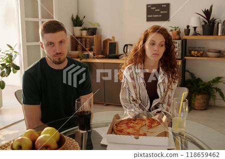 Troubled couple sitting by kitchen table Troubled couple sitting by kitchen table 118659462
