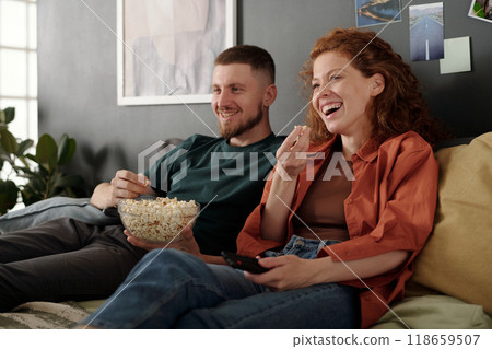 Laughing and eating popcorn from bowl 118659507
