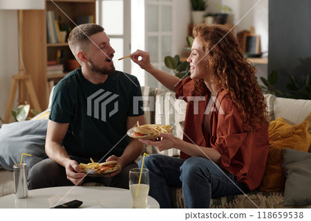 Happy couple having fast food at home Happy couple having fast food at home 118659538