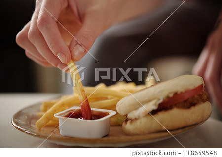 Hand dipping french fries into ketchup 118659548