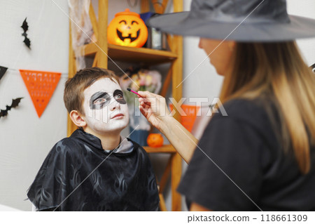 Mother applying Halloween makeup on boy's face Mother applying Halloween makeup on boy's face 118661309