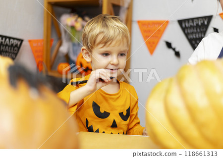 Young boy carving pumpkin at Halloween table 118661313
