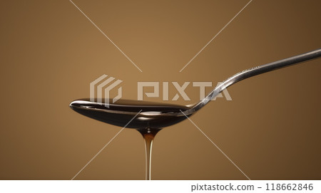Thick syrup dripping from a spoon. 118662846
