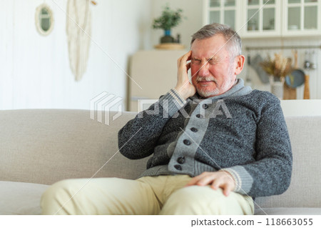 Headache pain. Unhappy middle aged senior man suffering from headache sick rubbing temples at home. Mature old senior grandfather touching temples experiencing stress. Man feeling pain hurt in head 118663055