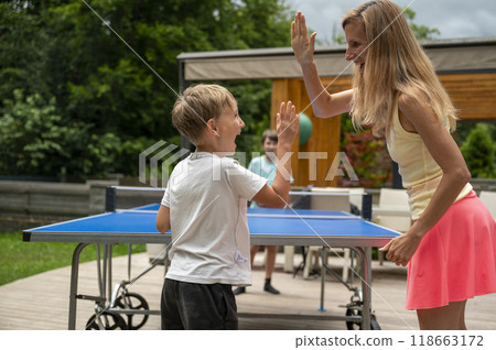 Young mother cheering for her toddler son playing table tennis Young mother cheering for her toddler son playing table tennis 118663172