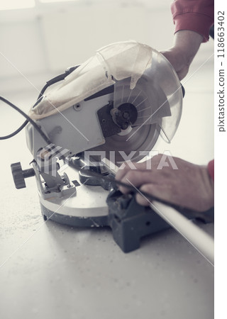 Retro effect faded and toned image of a workman using an electric circular saw 118663402