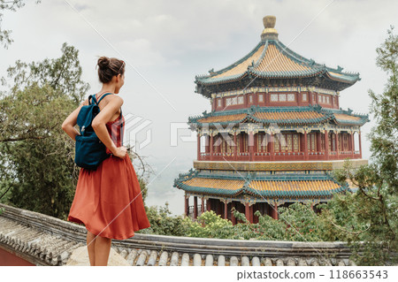 China Travel. Woman traveler relaxing enjoying travelling looking at nature view from old Chinese temple, tourist attraction in Beijing, china. Summer palace tourism destination, Asia travel China Travel. Woman traveler relaxing enjoying travelling looking at nature view from old Chinese temple, tourist attraction in Beijing, china. Summer palace tourism destination, Asia travel 118663543