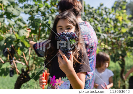 close up of grapes a girl holding in her hands with her family behind 118663643