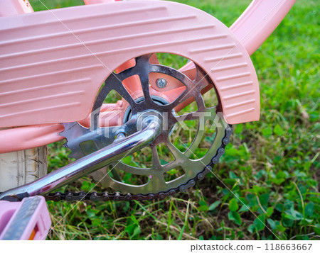 Vintage pink bicycle chainring with silver crank on green grass background Vintage pink bicycle chainring with silver crank on green grass background 118663667
