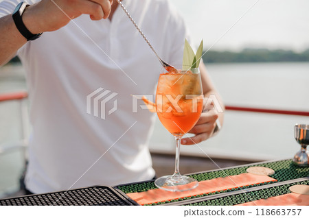 Refreshing Summer Cocktail Preparation with a Scenic Waterfront Background 118663757