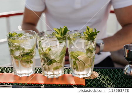 Refreshing Mojito Cocktails Served in Crystal Glasses with Fresh Mint and Lime on a Warm Sunny Day Refreshing Mojito Cocktails Served in Crystal Glasses with Fresh Mint and Lime on a Warm Sunny Day 118663778