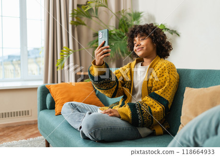 African American girl holding smartphone having video chat. Female blogger chatting with best friends in social network. Young woman having virtual meeting online chat video call at home 118664933