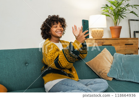 African American girl holding smartphone having video chat. Female blogger chatting with best friends in social network. Young woman having virtual meeting online chat video call at home 118664936