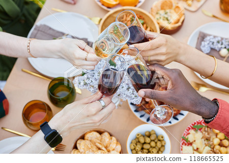 Hands of multi-ethnic group clinking wine glasses in festive gathering celebrating togetherness and diversity while enjoying delicious food and snacks on beautifully arranged table Hands of multi-ethnic group clinking wine glasses in festive gathering celebrating togetherness and diversity while enjoying delicious food and snacks on beautifully arranged table 118665525