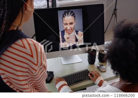 Over shoulder view at two women looking at portrait pictures on computer screen during photo selection in professional photoshoot Over shoulder view at two women looking at portrait pictures on computer screen during photo selection in professional photoshoot 118666200