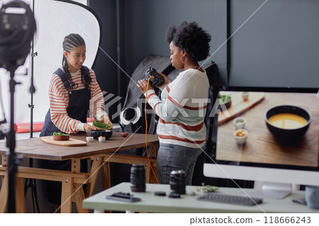 Two photographers working on food photography set in professional studio and taking photos of dishes with computer in foreground copy space 118666243