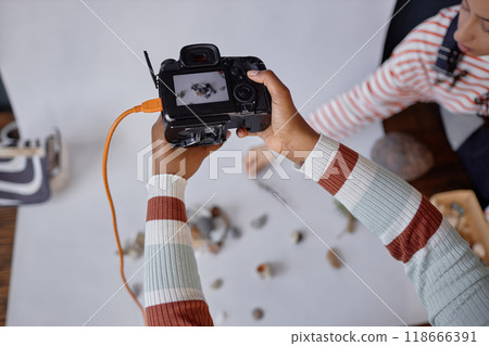 Top view closeup of female hands holding professional camera during product photography photoshoot in studio copy space 118666391