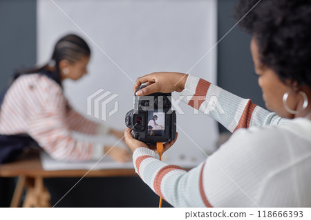 Back view closeup of African American woman holding professional DSLR camera and taking pictures in photo studio copy space Back view closeup of African American woman holding professional DSLR camera and taking pictures in photo studio copy space 118666393