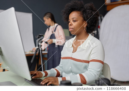Portrait of African American woman as female photographer using desktop computer in professional photo studio doing selection or retouch 118666408