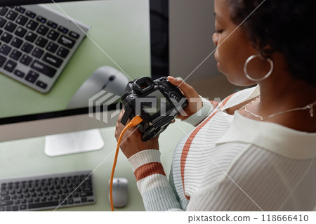 High angle closeup of Black young woman as female photographer holding DSLR camera and looking at pictures on digital screen copy space 118666410