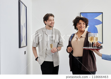 Waist up portrait of two smiling people taking champagne glasses while visiting grand opening ceremony of modern art museum, copy space Waist up portrait of two smiling people taking champagne glasses while visiting grand opening ceremony of modern art museum, copy space 118666463