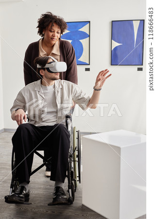 Vertical full length portrait of man with disability using VR technology and interacting with digital art piece in museum smiling friend or partner assisting Vertical full length portrait of man with disability using VR technology and interacting with digital art piece in museum smiling friend or partner assisting 118666483