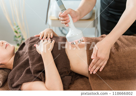 Esthetician and woman performing slimming beauty treatment using cavitation beauty machine at beauty salon 118666802