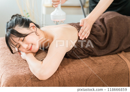 Esthetician and woman performing slimming beauty treatment using cavitation beauty machine at beauty salon Esthetician and woman performing slimming beauty treatment using cavitation beauty machine at beauty salon 118666859