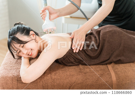 Esthetician and woman performing slimming beauty treatment using cavitation beauty machine at beauty salon Esthetician and woman performing slimming beauty treatment using cavitation beauty machine at beauty salon 118666860