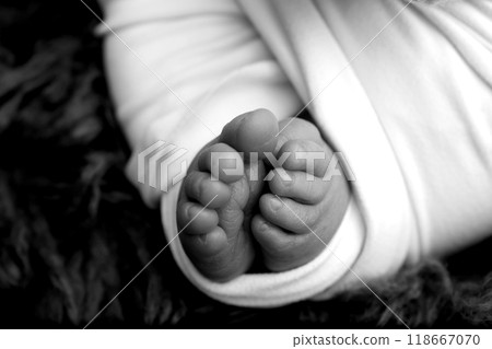 Foot of a newborn. Close up feet, toes, heels, feet of a newborn baby. Studio monochrome, vintage style, black and white macro photography. Foot of a newborn. Close up feet, toes, heels, feet of a newborn baby. Studio monochrome, vintage style, black and white macro photography. 118667070