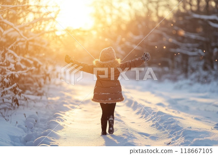 Happy girl walking in snowy forest at sunset during winter 118667105