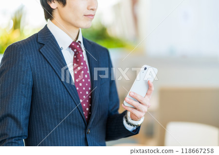 A businessman operating a smartphone (parts) Photo courtesy of Denpa Gakuen, Tokyo Electronics College 118667258