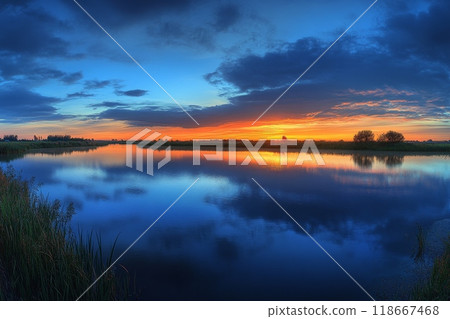 Breathtaking sunset reflecting on calm lake water in kinderdijk 118667468