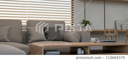 A close-up of a wooden coffee table in a contemporary living room features a comfortable grey sofa. 118668370