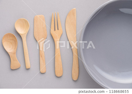 Various wooden kitchenware lined up with empty gray bowls on a clean gray background. Various wooden kitchenware lined up with empty gray bowls on a clean gray background. 118668655