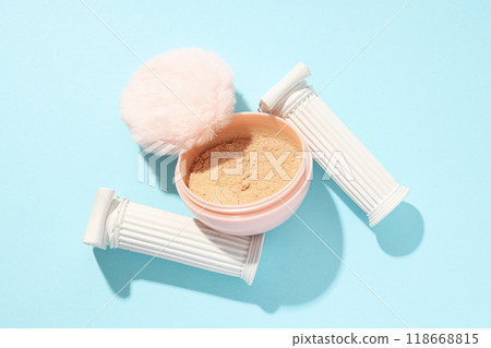 A bottle of loose powder, light shade, on a blue background. 118668815
